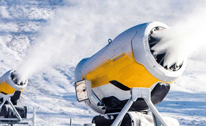 Schneekanone schiesst Schnee in verschneite Umgebung