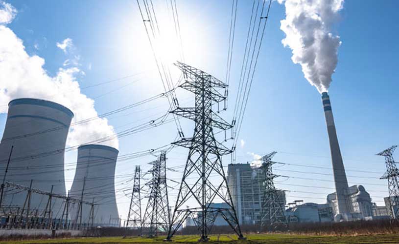 Kraftwerk mit Kuehlreaktoren, Strommasten, im Vordergrund Rasen