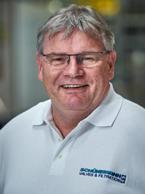 Mann in weissem Shirt mit Brille lacht in die Kamera