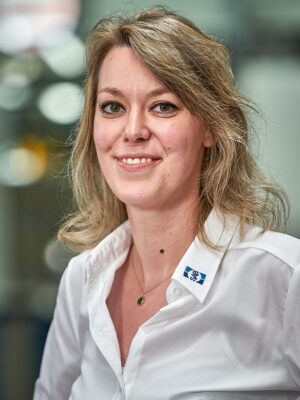 Frau in weissem Hemd laechelt in die Kamera
