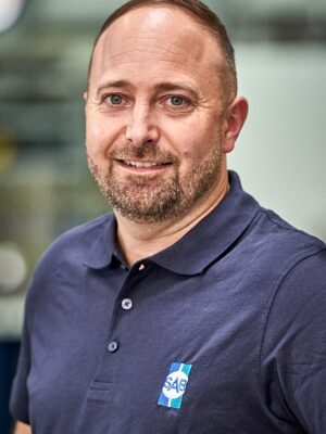 Mann in dunkelblauem Shirt laechelt in die Kamera