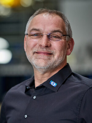 Mann in dunkelblauem Shirt laechelt in die Kamera
