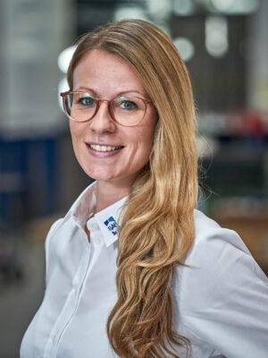 Frau in weissem Hemd laechelt in die Kamera