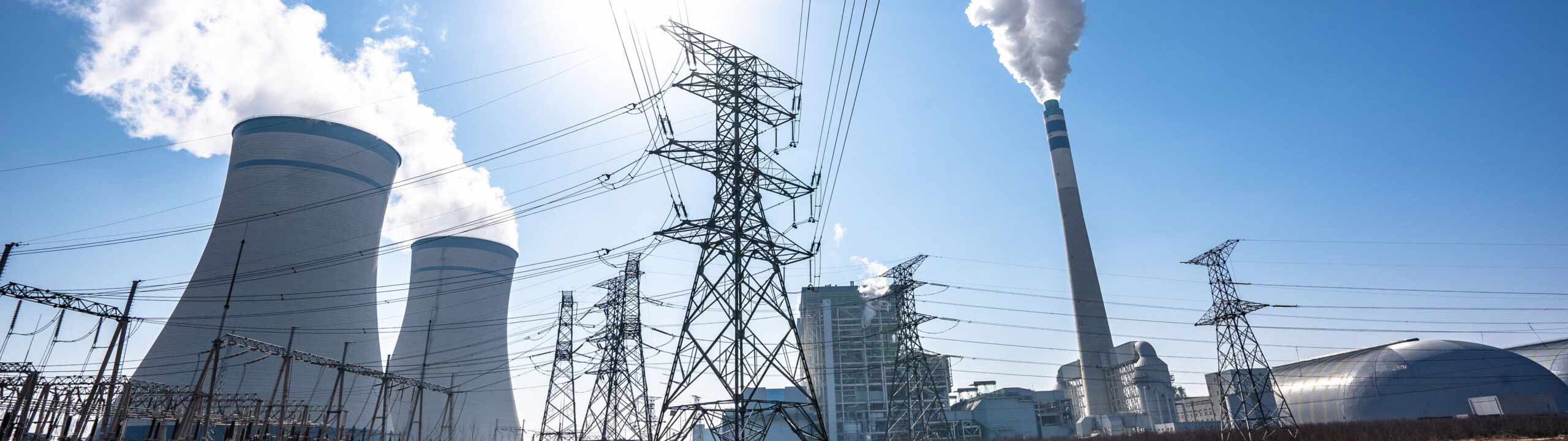 Kraftwerk mit Kuehlreaktoren, Strommasten, im Vordergrund Rasen