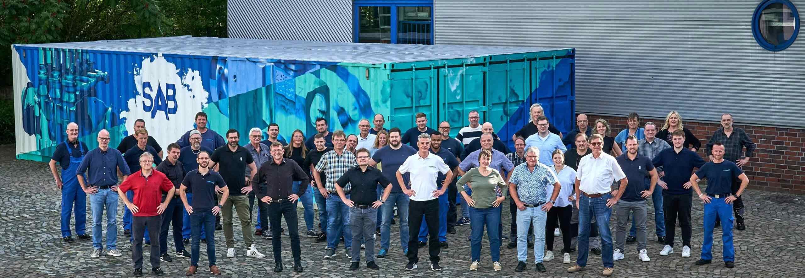 Viele Menschen stehen vor SAB-Gebaeude, Haende in die Hueften gestemmt